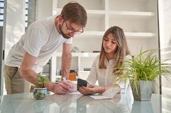 couple doing calculation and paperwork, looking at smartphone