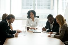 Businessman and businesswoman signing contracts with intermediary in between the two groups