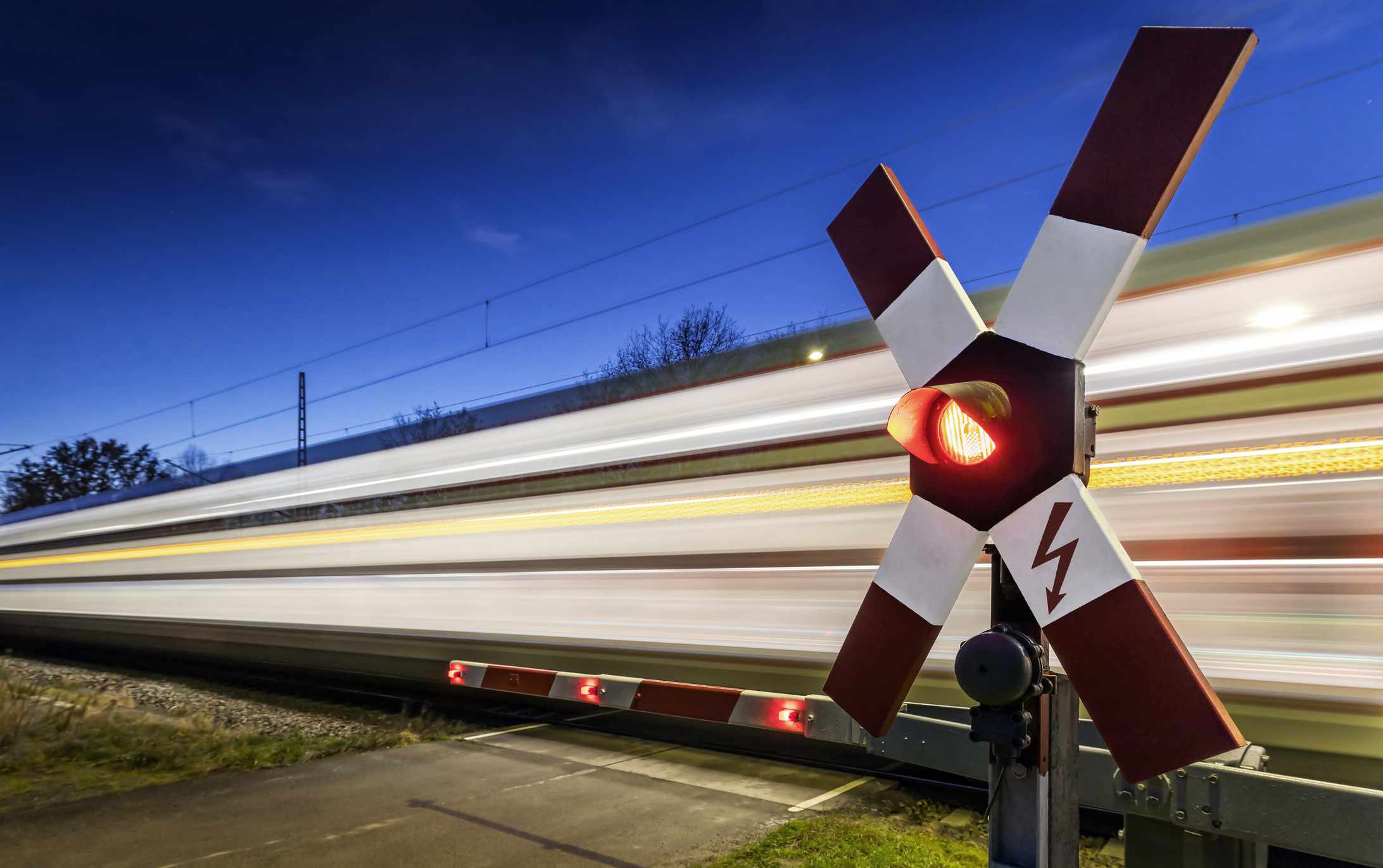 Railroad crossing with fast train at blue hour