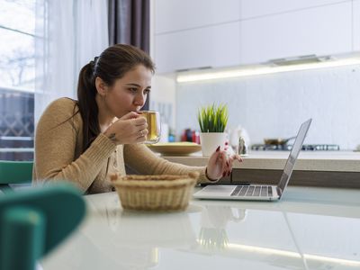 Young woman sipping tea while looking at mortgage rate in the kitchen