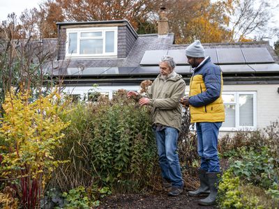 Two men standing looking at nettles together at a residential home in the North East of England.