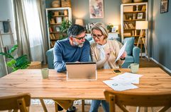 Mature couple paying bills together and managing home budget