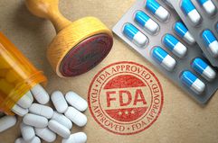 FDA Approved Concept. Rubber Stamp With FDA and Pills on Craft Paper