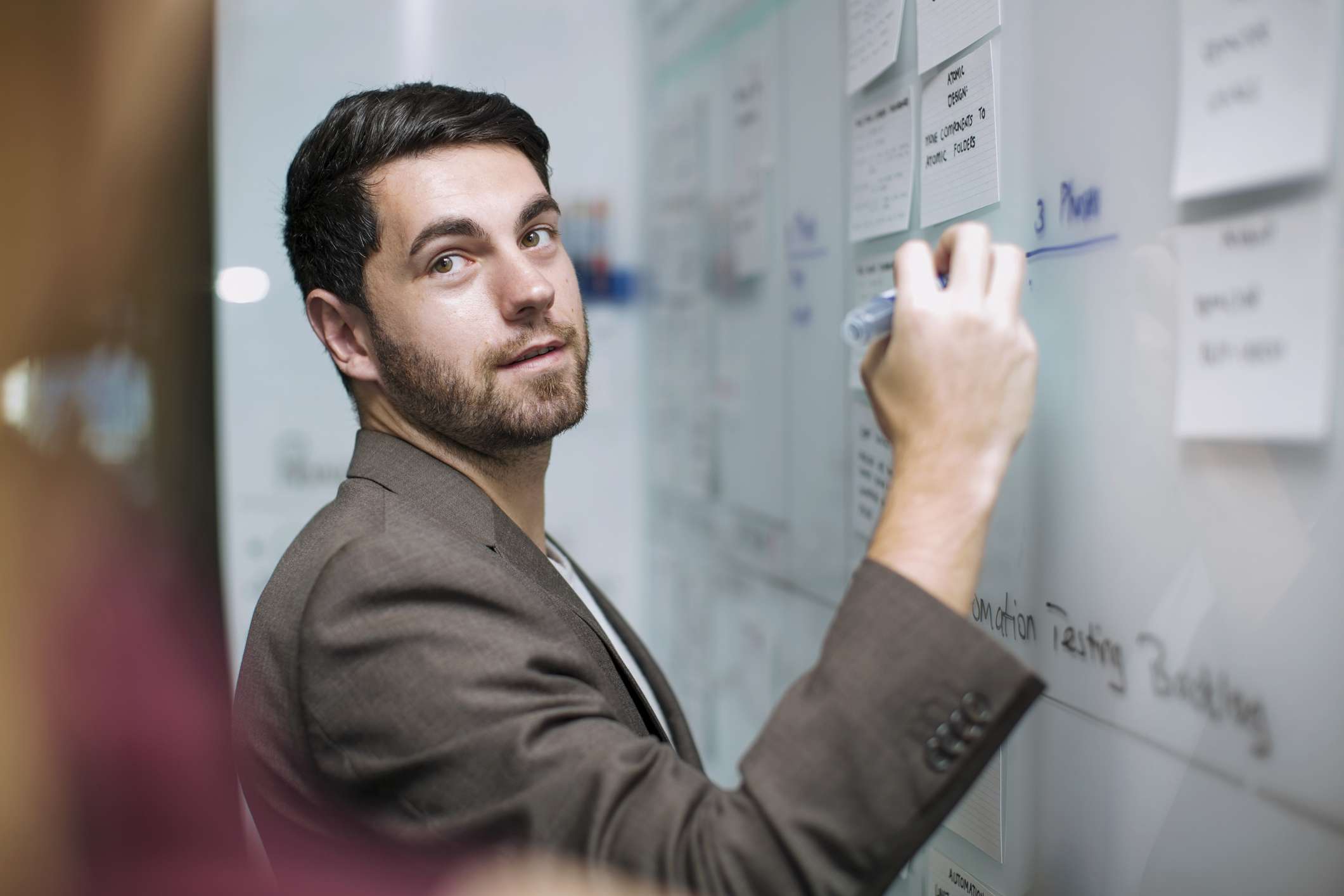 Man with beard in suit drawing whiteboard