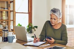 A person using a calculator and laptop to figure out tax bill