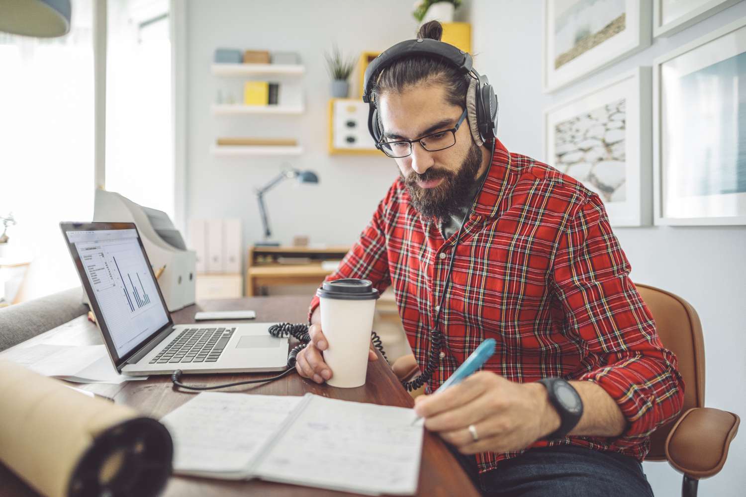 A forex trader uses a laptop and makes calculations and notes before entering into a zero-coupon inflation swap to transfer inflation risk with another currency.