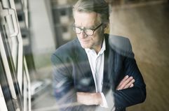 A businessman looking out the window with his arms crossed.