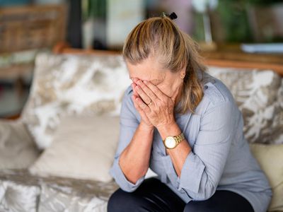 Woman on couch with her head in her hands