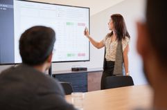 A businesswoman using graphs on a screen in business meeting.