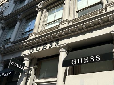 The facade of a Guess store in New York City, displaying awnings and signs with the brand's name.