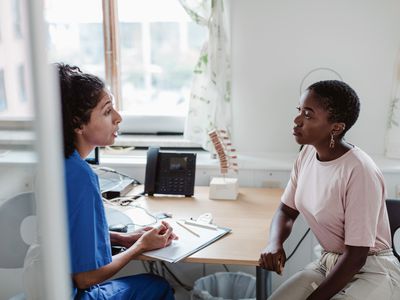 A woman medical provider speaks with a female patient in an office