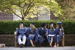 Five graduates sitting on a bench