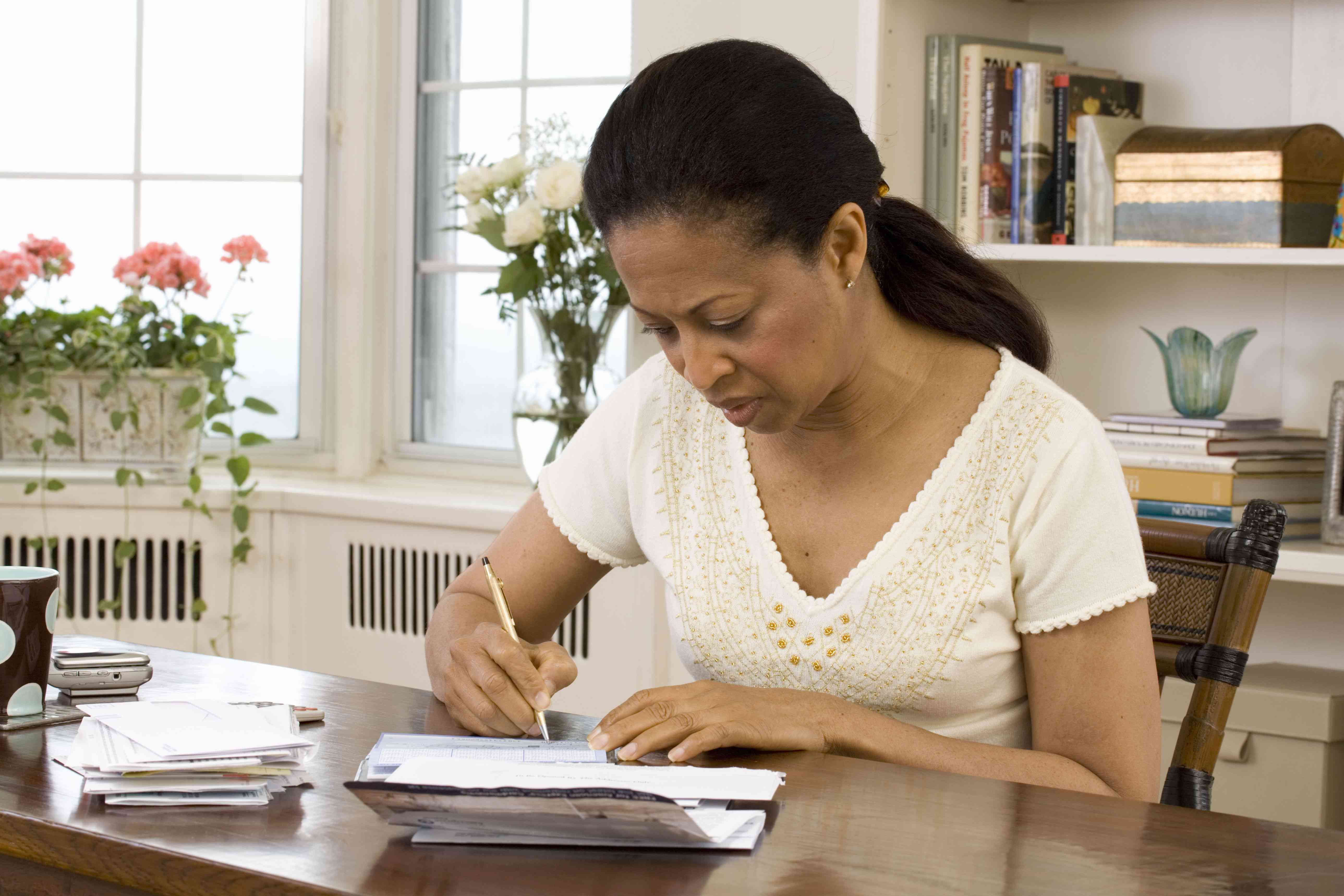 Woman seated at a desk, writing a check