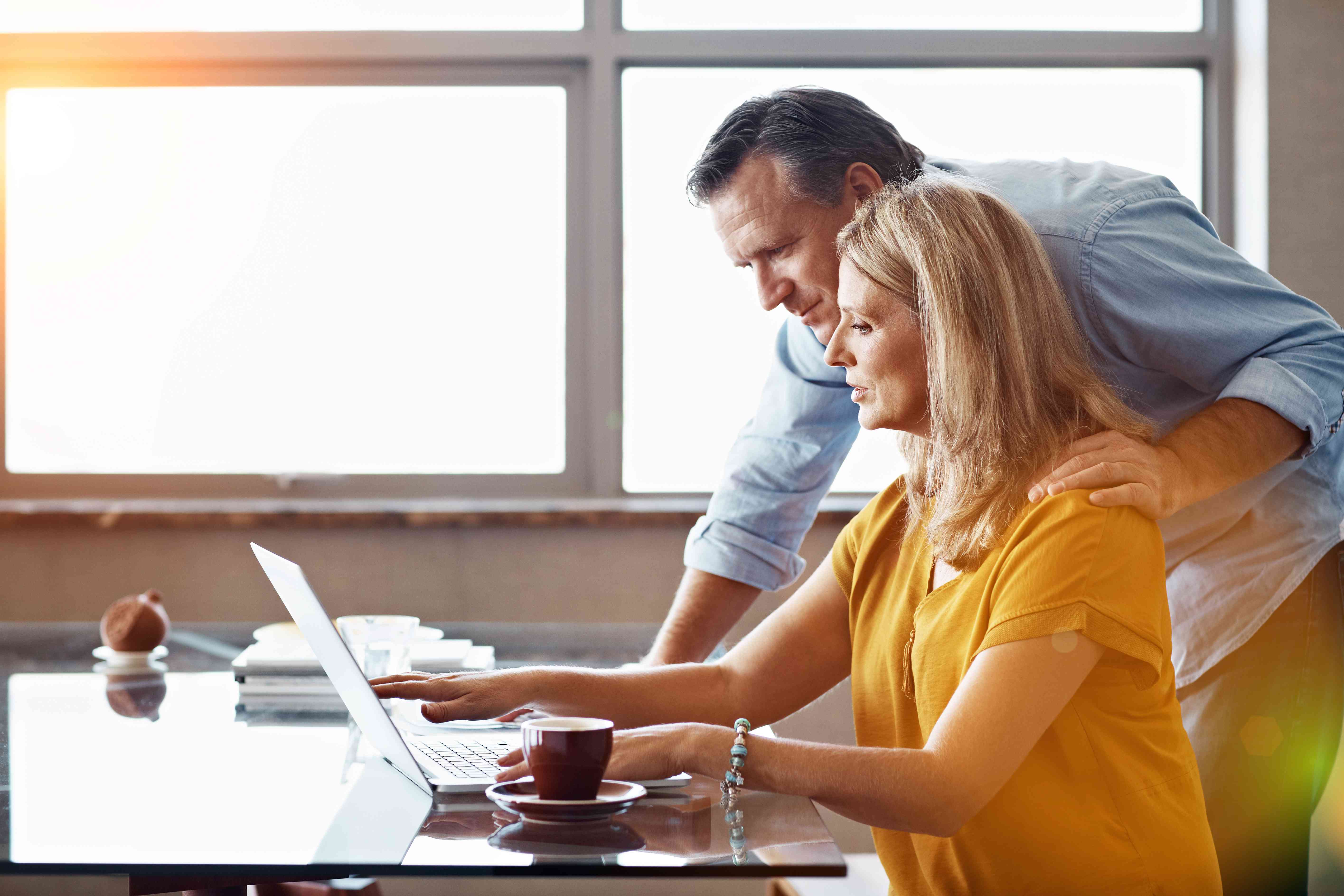 Older couple at home looking together at a laptop at their kitchen table