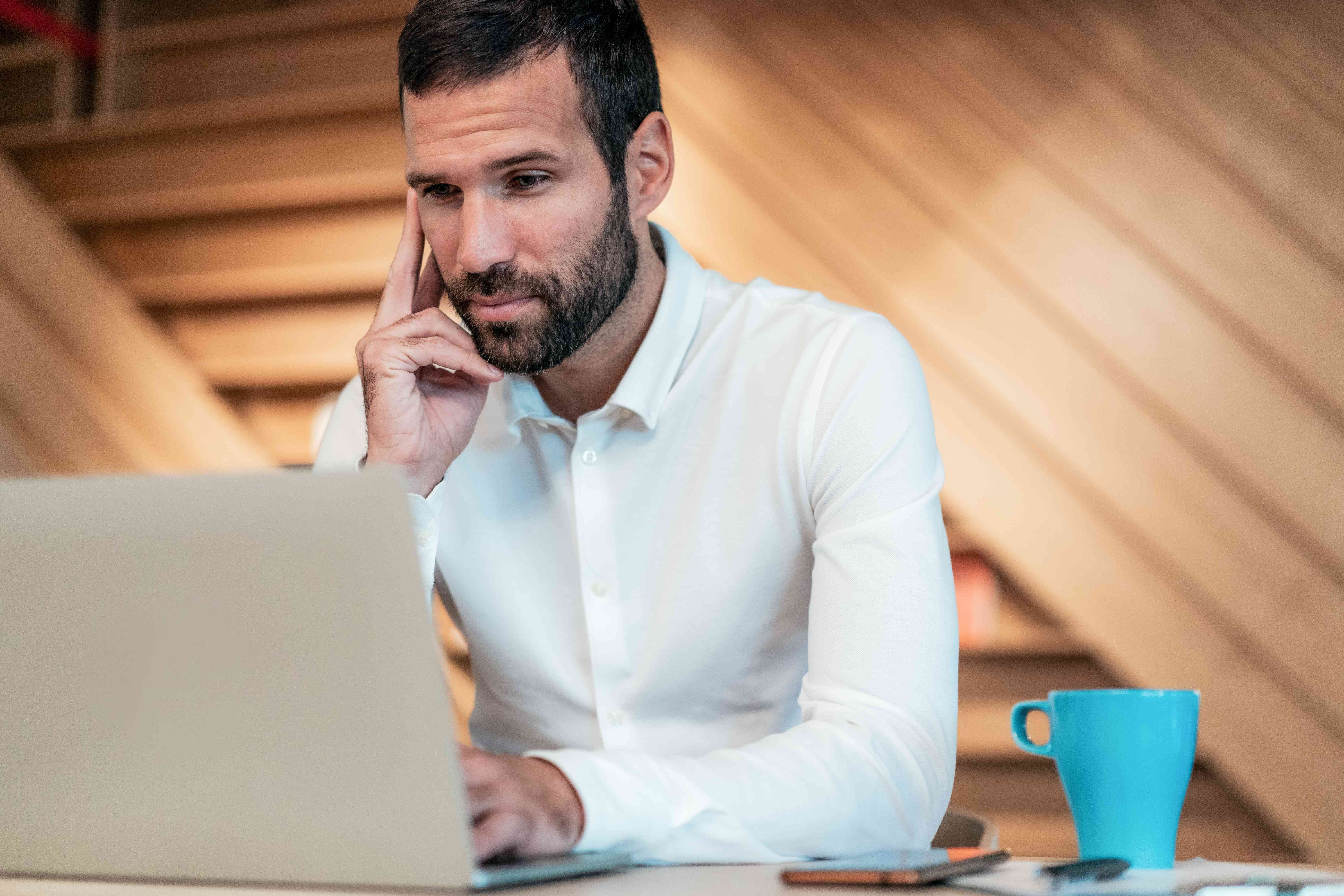 Man in his 30s seriously studying something on his laptop 