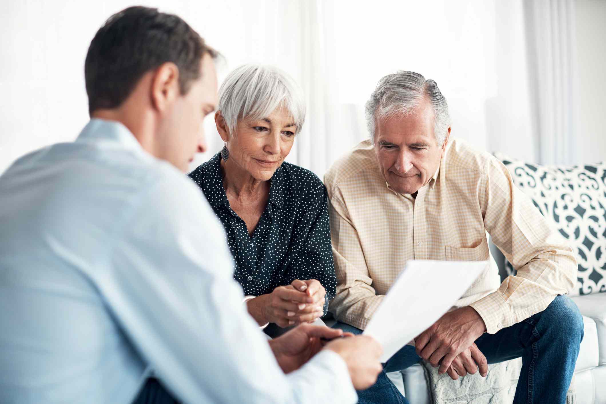 An elderly couple discussing paperwork with a man