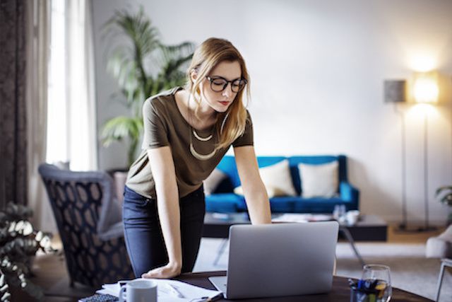 woman standing looking down at computer screen