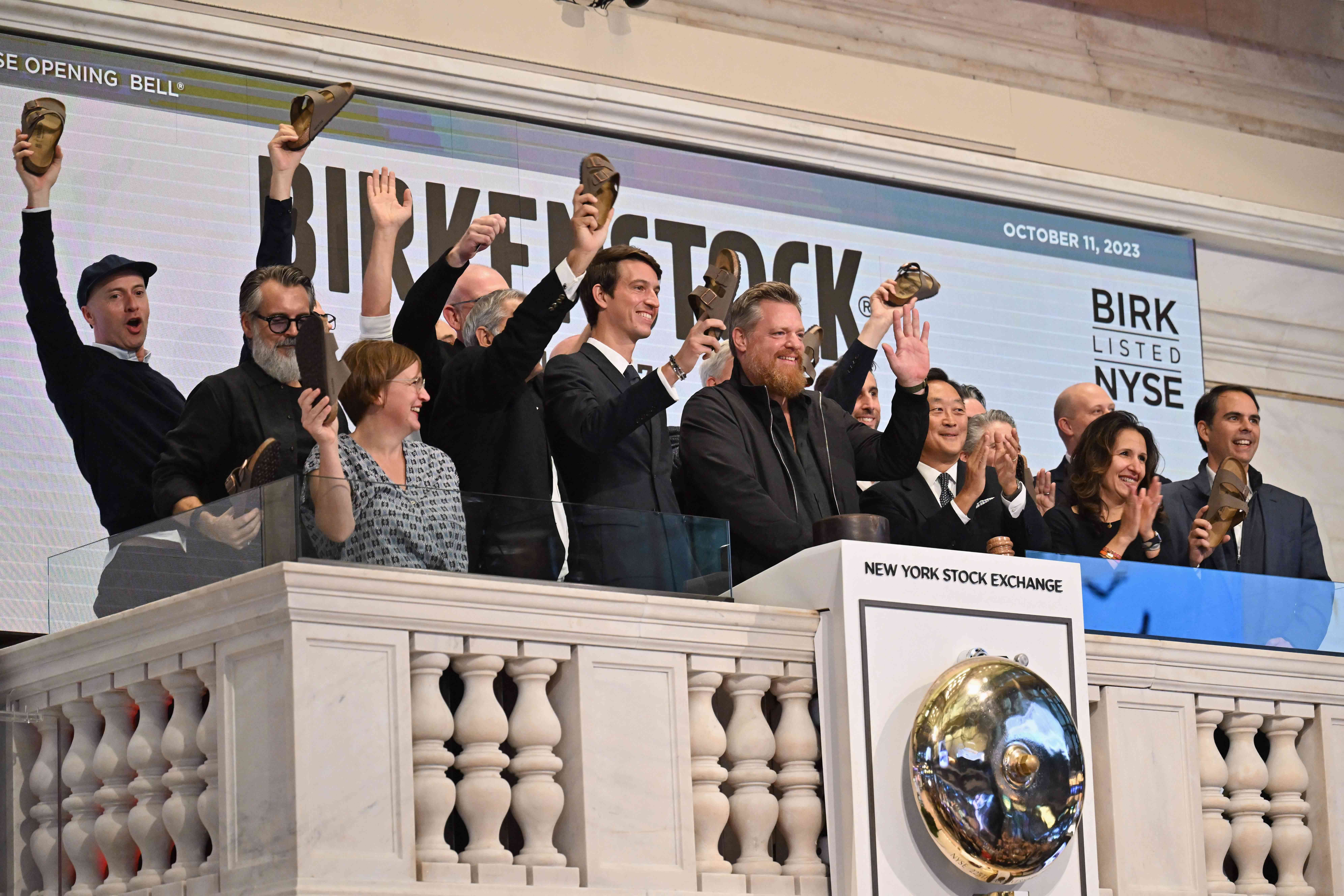 Birkenstock CEO Oliver Reichert (C) waves as he rings the opening at New York Stock Exchange (NYSE) New York on October 11, 2023.