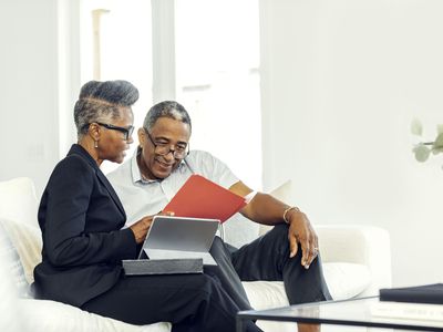 Two people seated on a couch, looking at folders