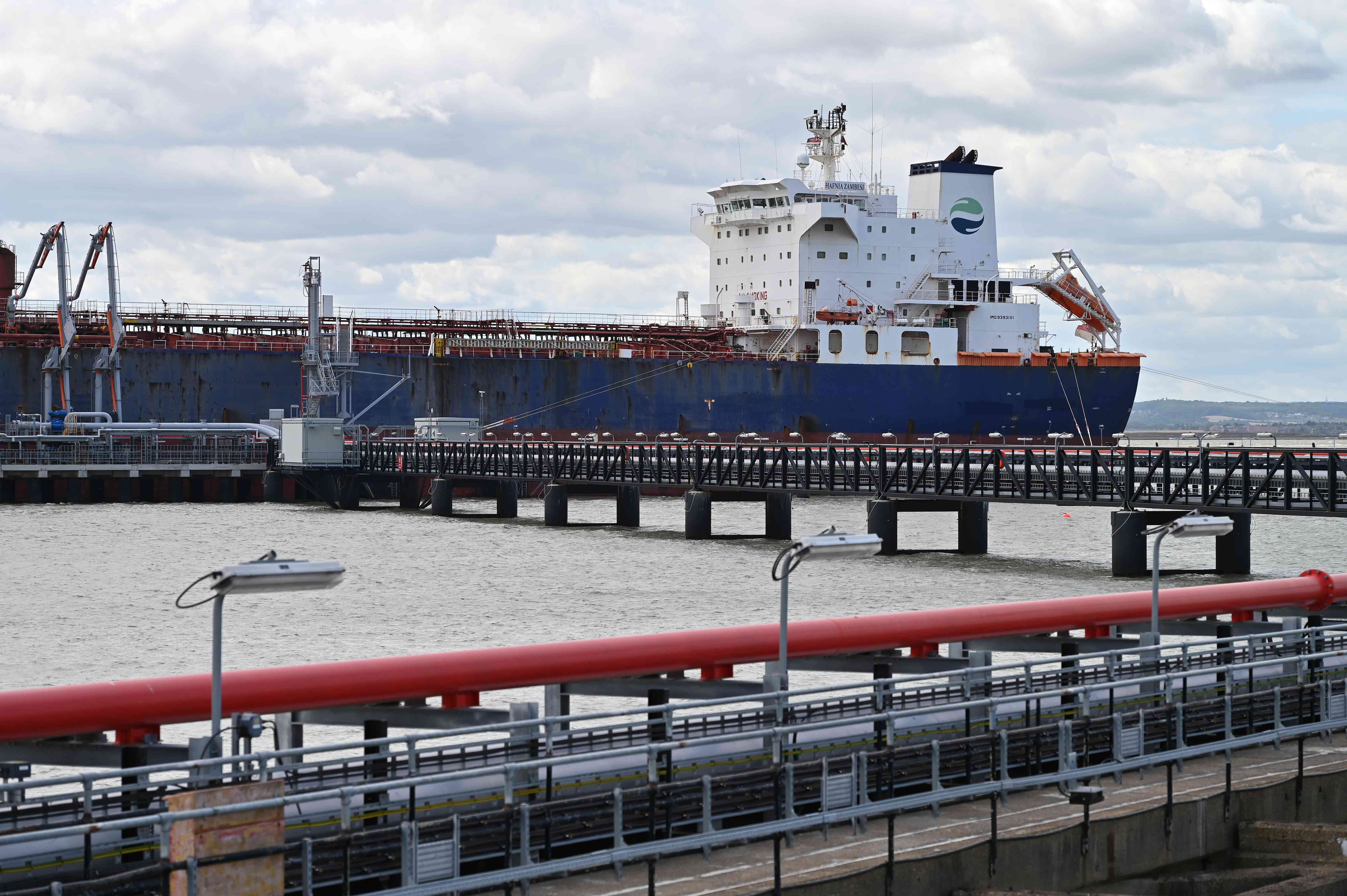 An oil tanker with the Hafnia logo transfers its fuel cargo via pipeline to the shore.