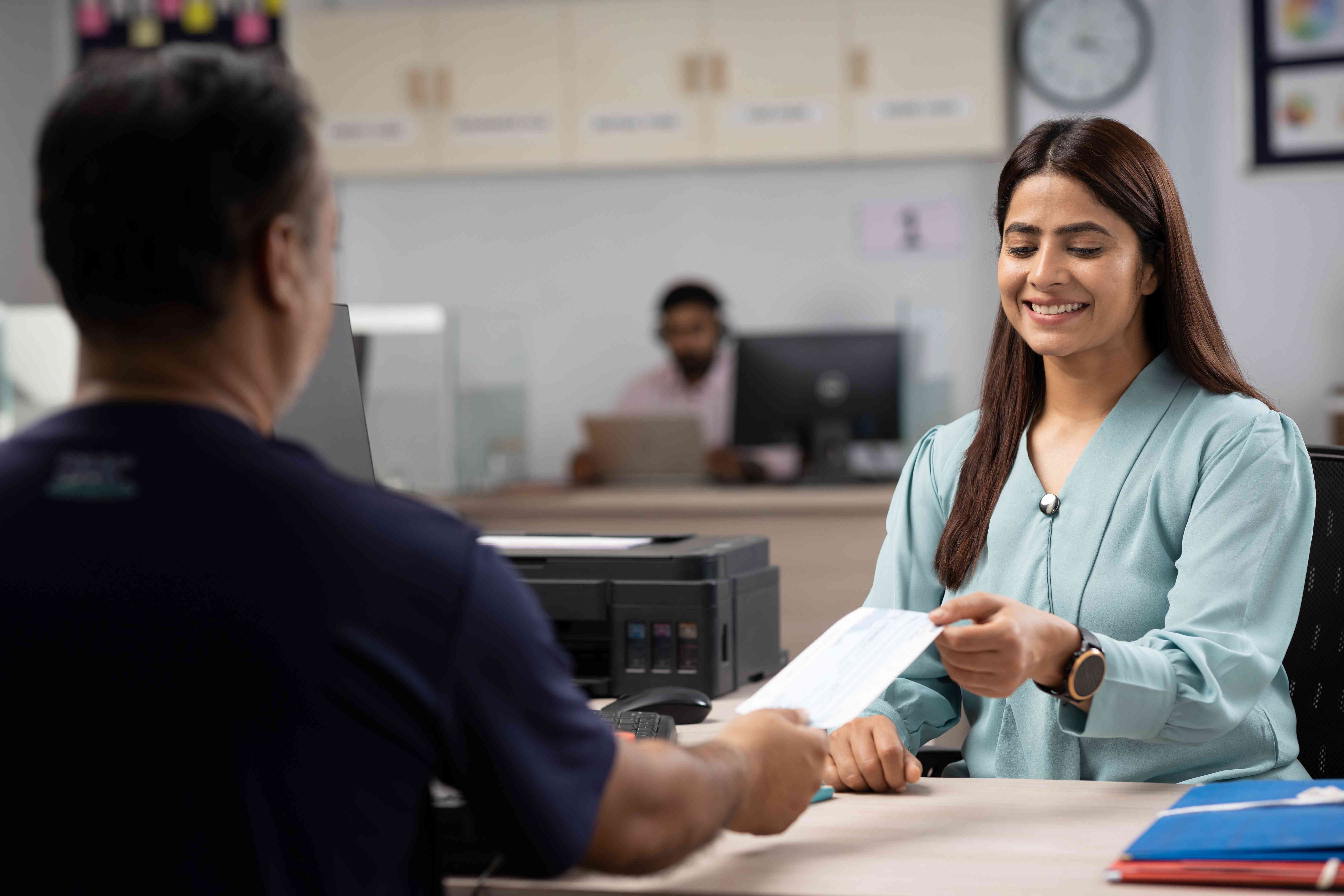 Female bank employee handing check to customer