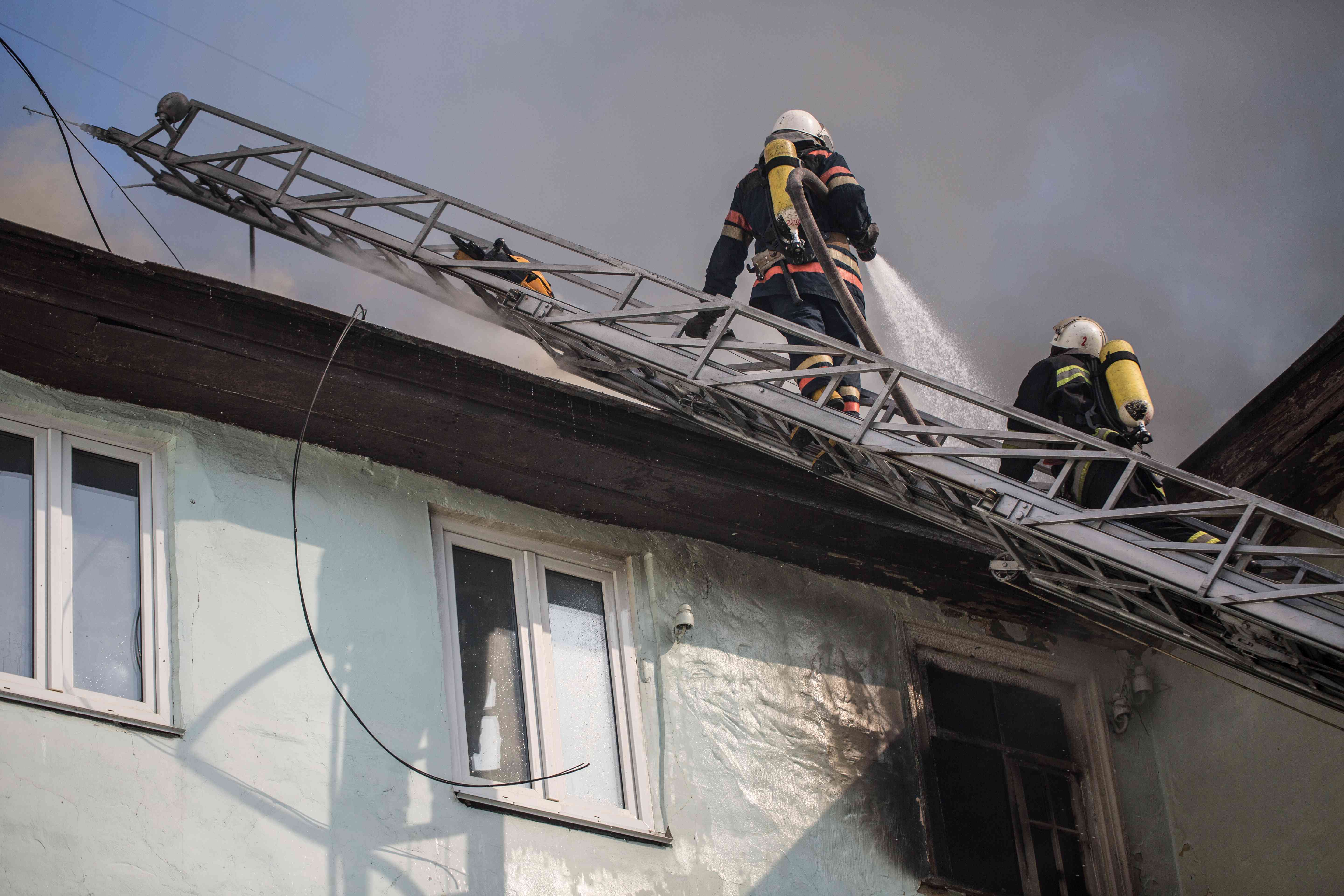 Firefighters trying to extinguish a fire on the roof of a house