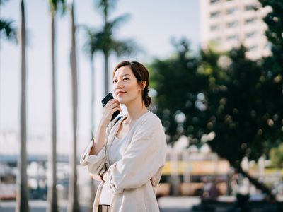 Young woman holding smartphone while standing outside