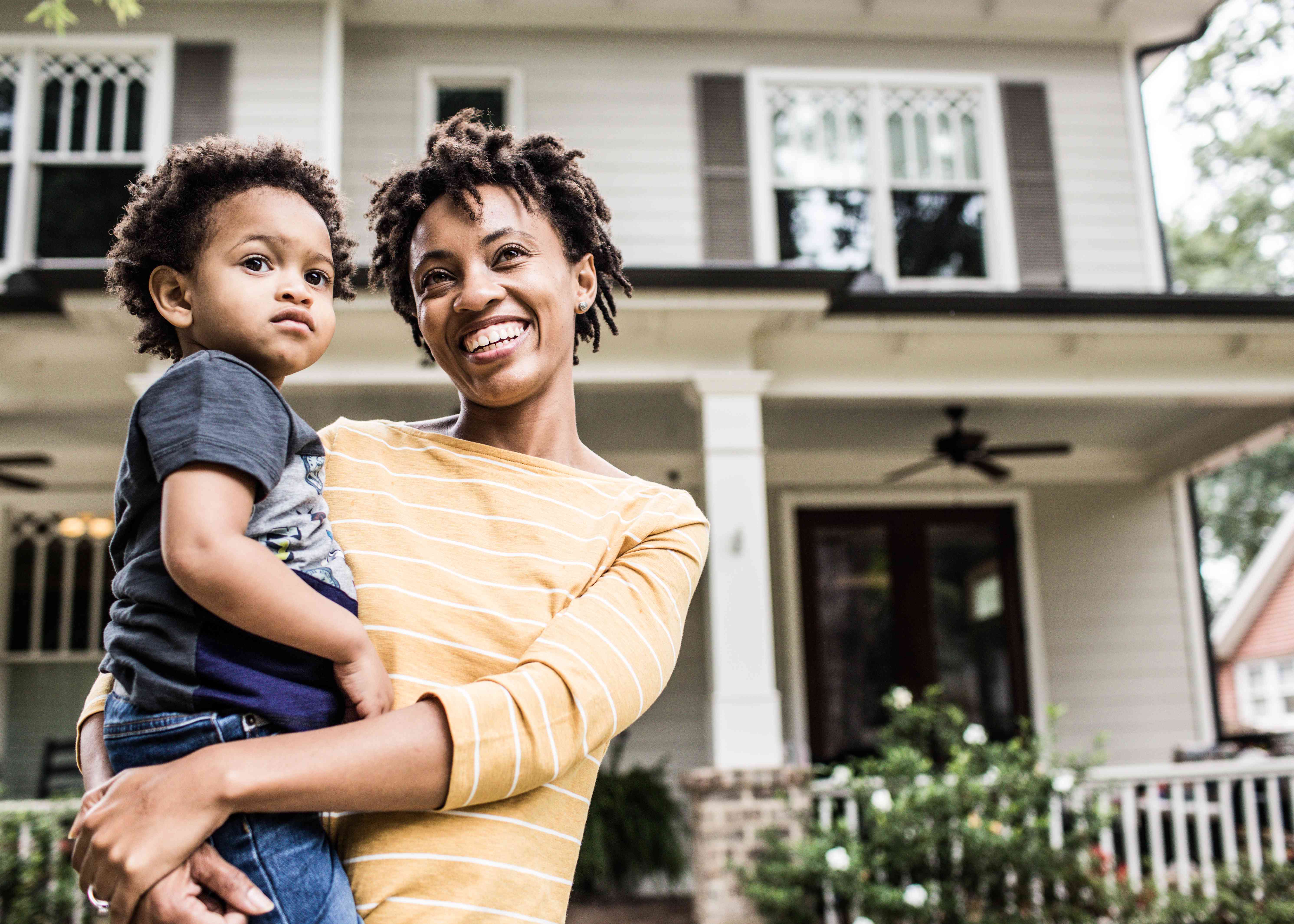 A mother and daughter standing in front of their home. 