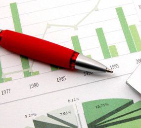 A red pen laying on a vague bar chart and pie graph, neither showing any data other than years and percentages.