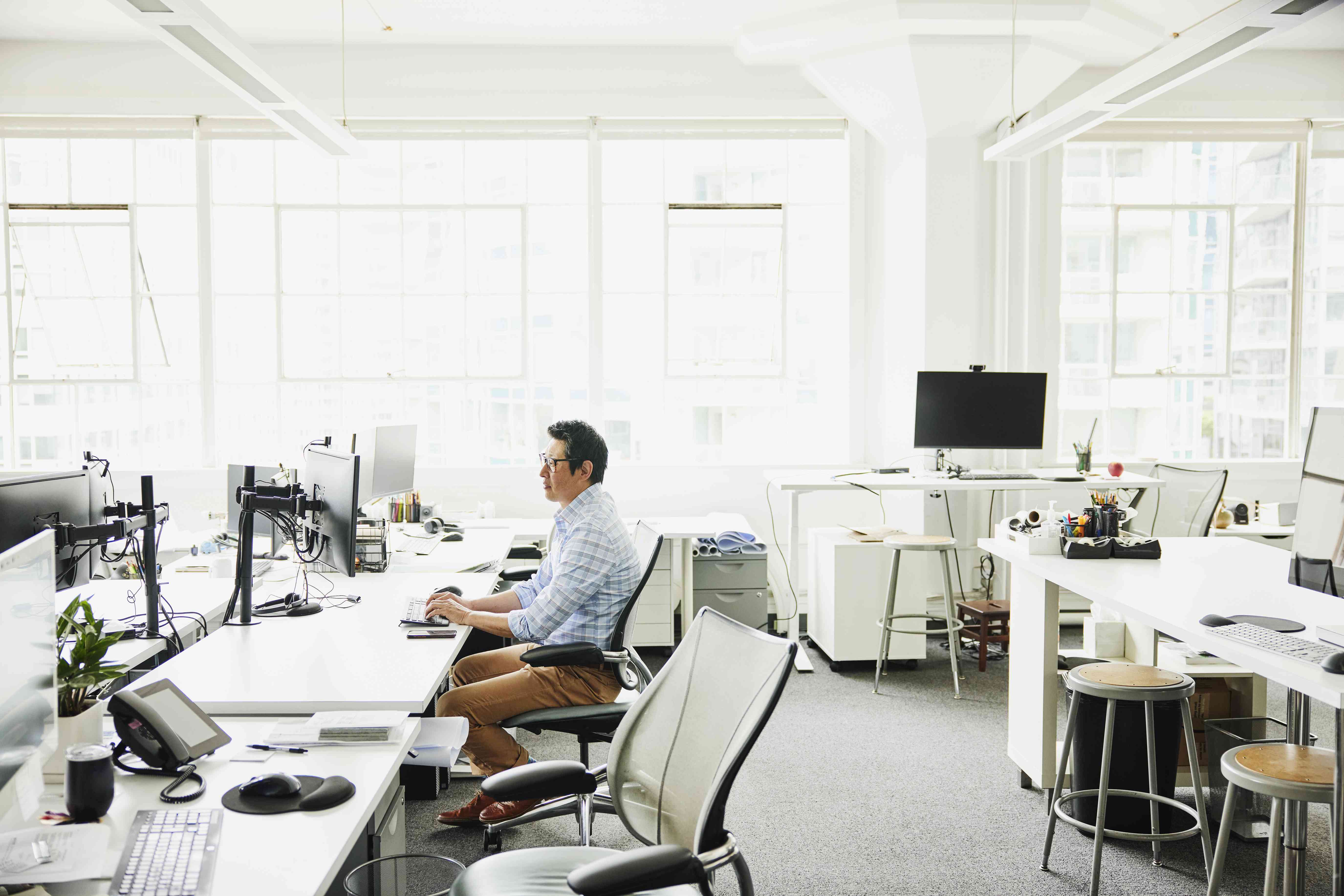 Wide shot of businessman working on computer at workstation in empty office