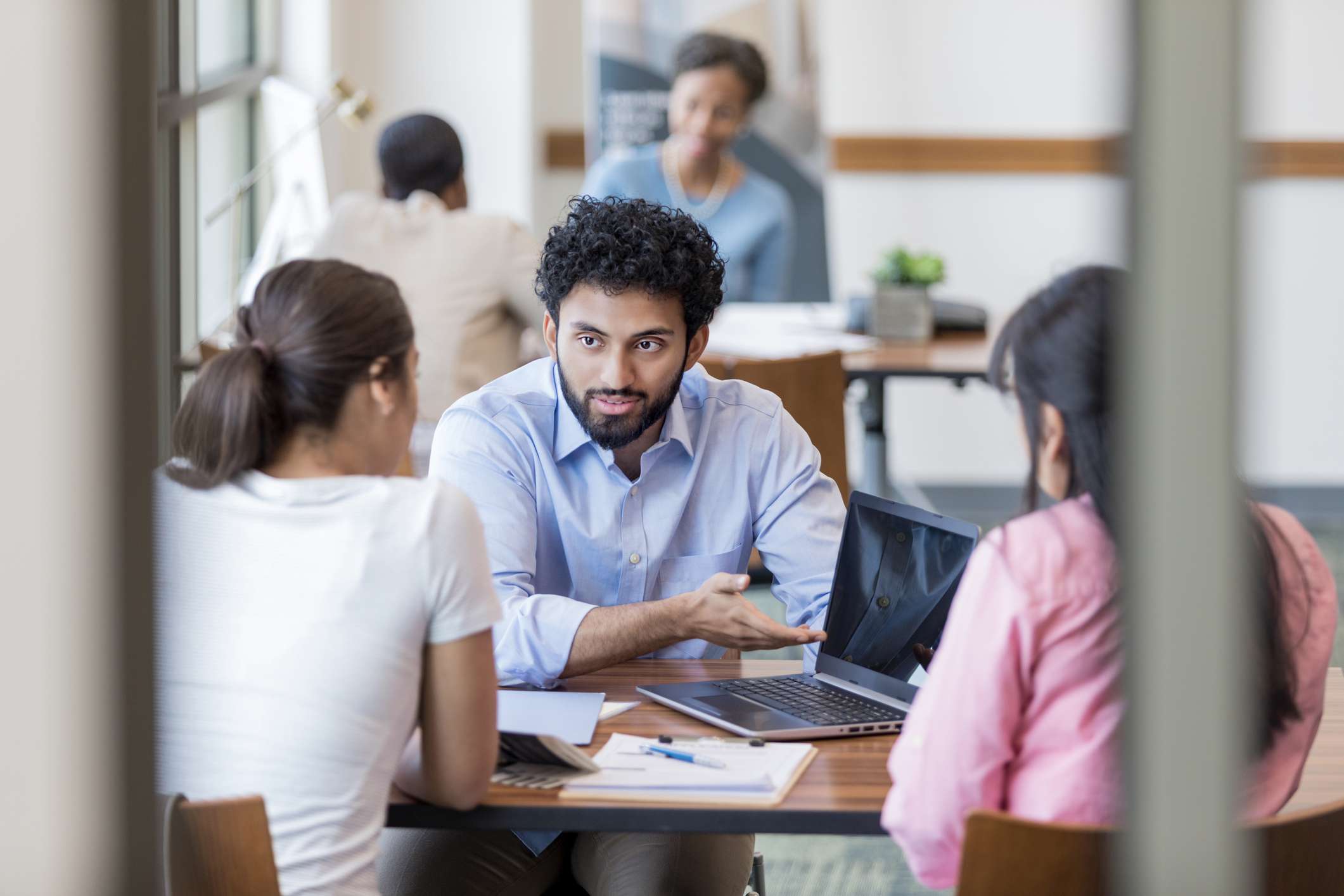 A teller interacts with two bank customers.