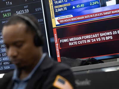 A trader sits in front of TV screens displaying information about the Fed's rate cut announcement.