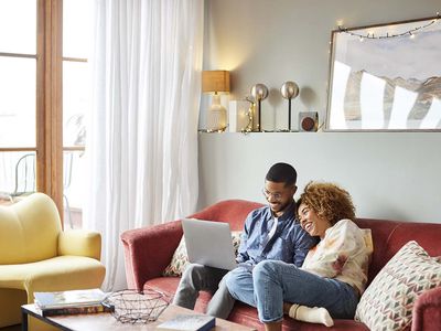 Woman Leaning On Man Using Laptop to search personal loans for excellent credit