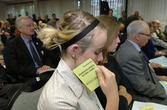 A shareholder contemplates their actions as they hold their voting card while attending an annual shareholders meeting