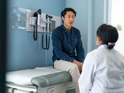 Asian man sitting on an exam table speaking to his doctor