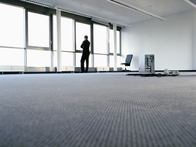 Business worker stands in empty office looking out the window