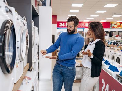 Young couple shopping for washing machine in appliance store