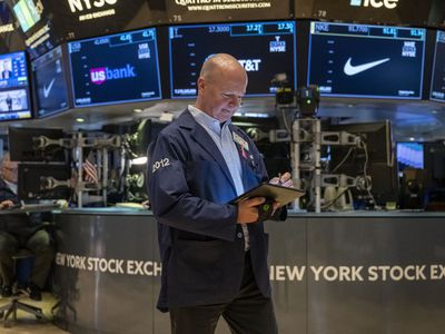 A trader looking down at a tablet he is holding and walking on the floor of the nYSE