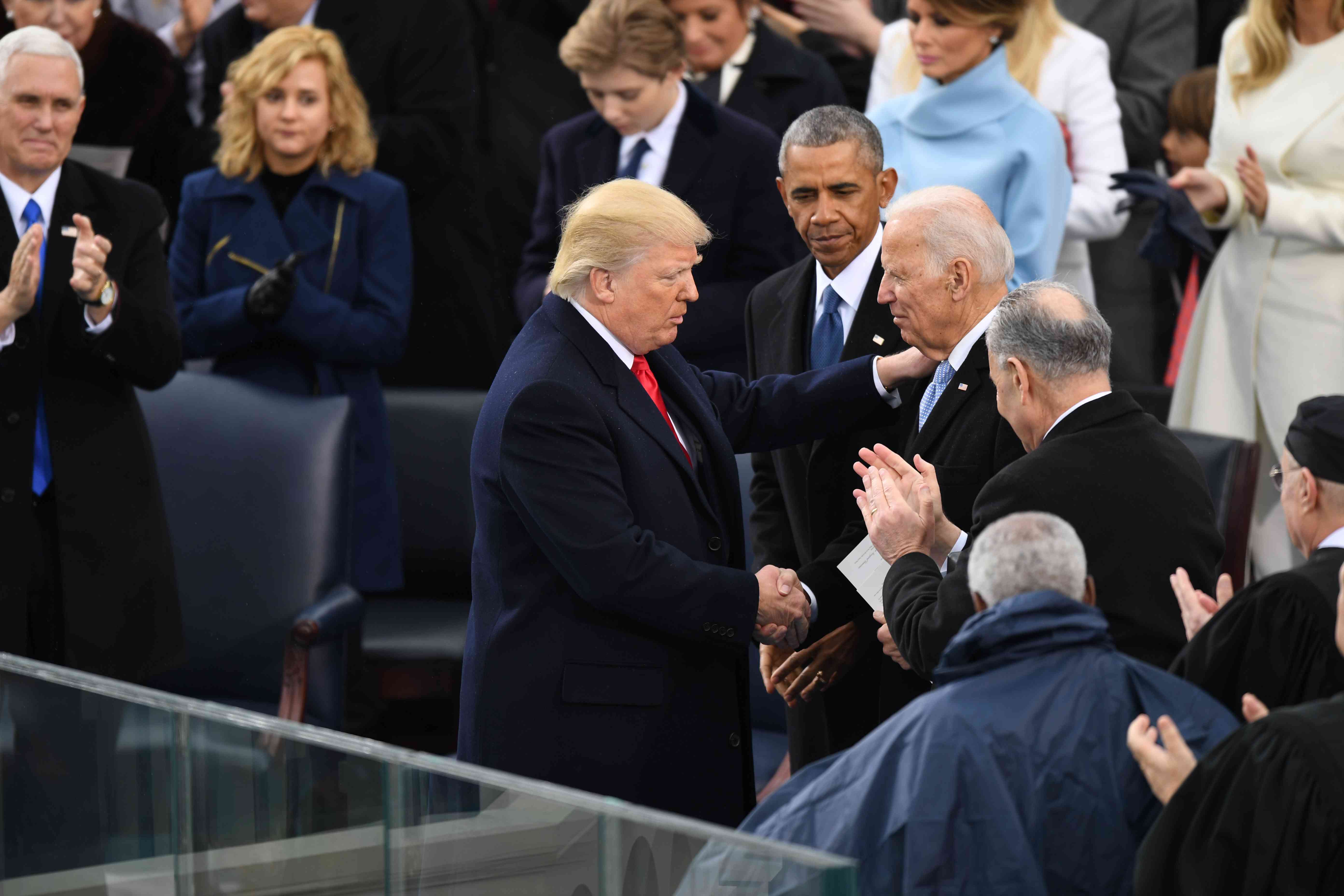 President Donald J. Trump shakes hands with Former vice president Joe Biden as Former president Barack Obama looks on at the inauguration of President Donald J. Trump on January 20, 2017.