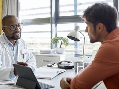 Male doctor discussing with patient in clinic about Health Insurance