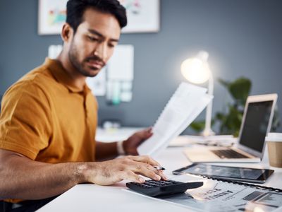 Man sitting at his desk with a calculator and paperwork