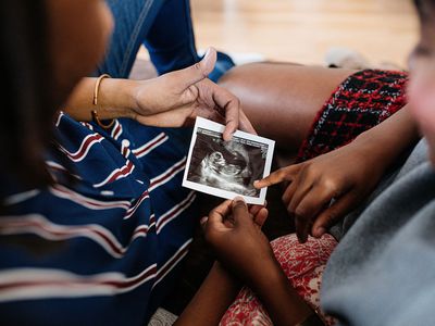 Young couple looking at pregnancy trimester ultrasound IVF loan