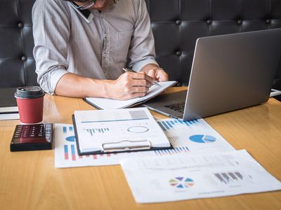 Midsection of Businessman Talking Over Smart Phone While Working at Desk in Office