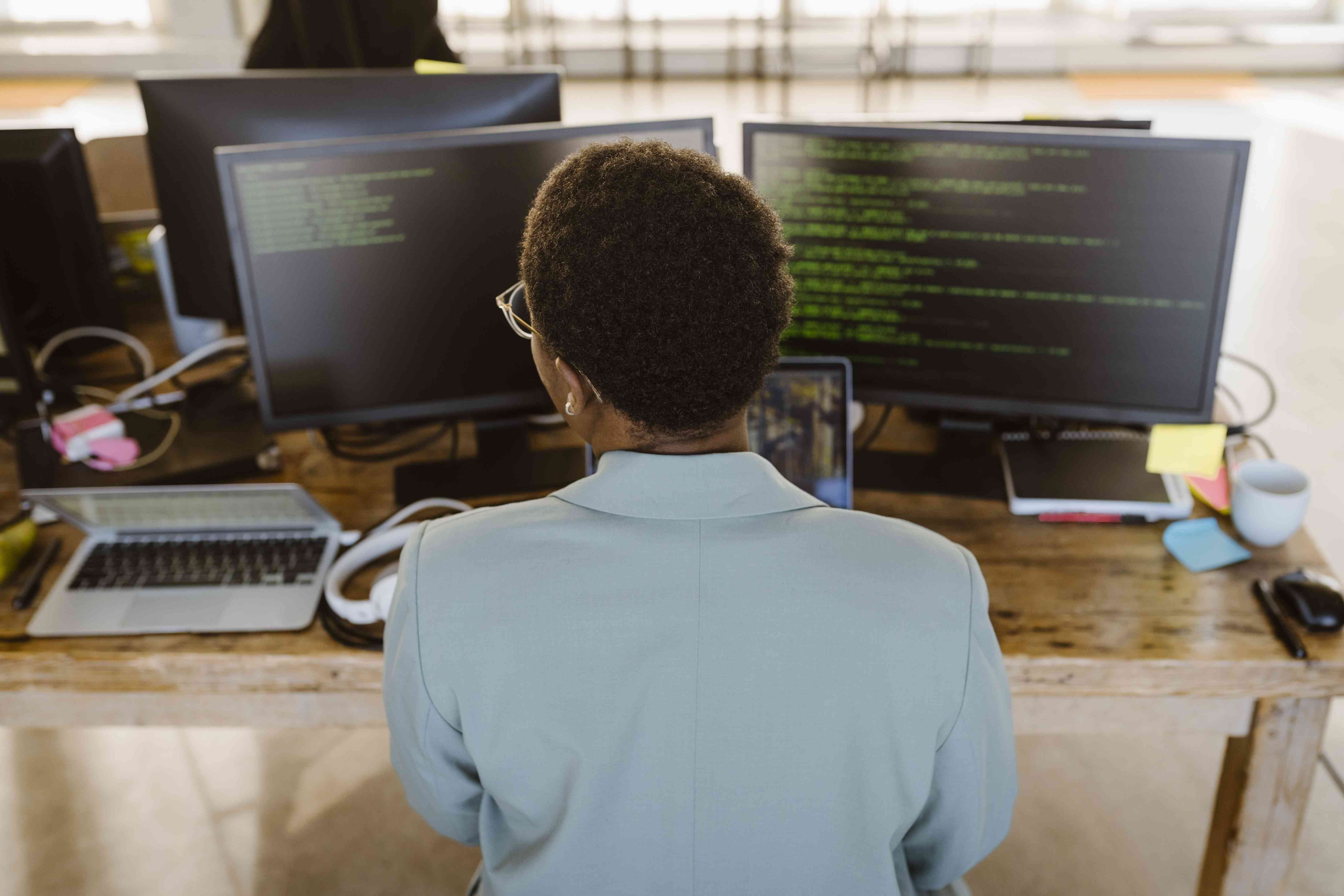 Closeup rear view of a person coding on multiple computers