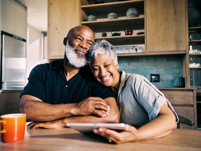 A retired couple celebrate at the kitchen table after reviewing the balance of their retirement annuity account.