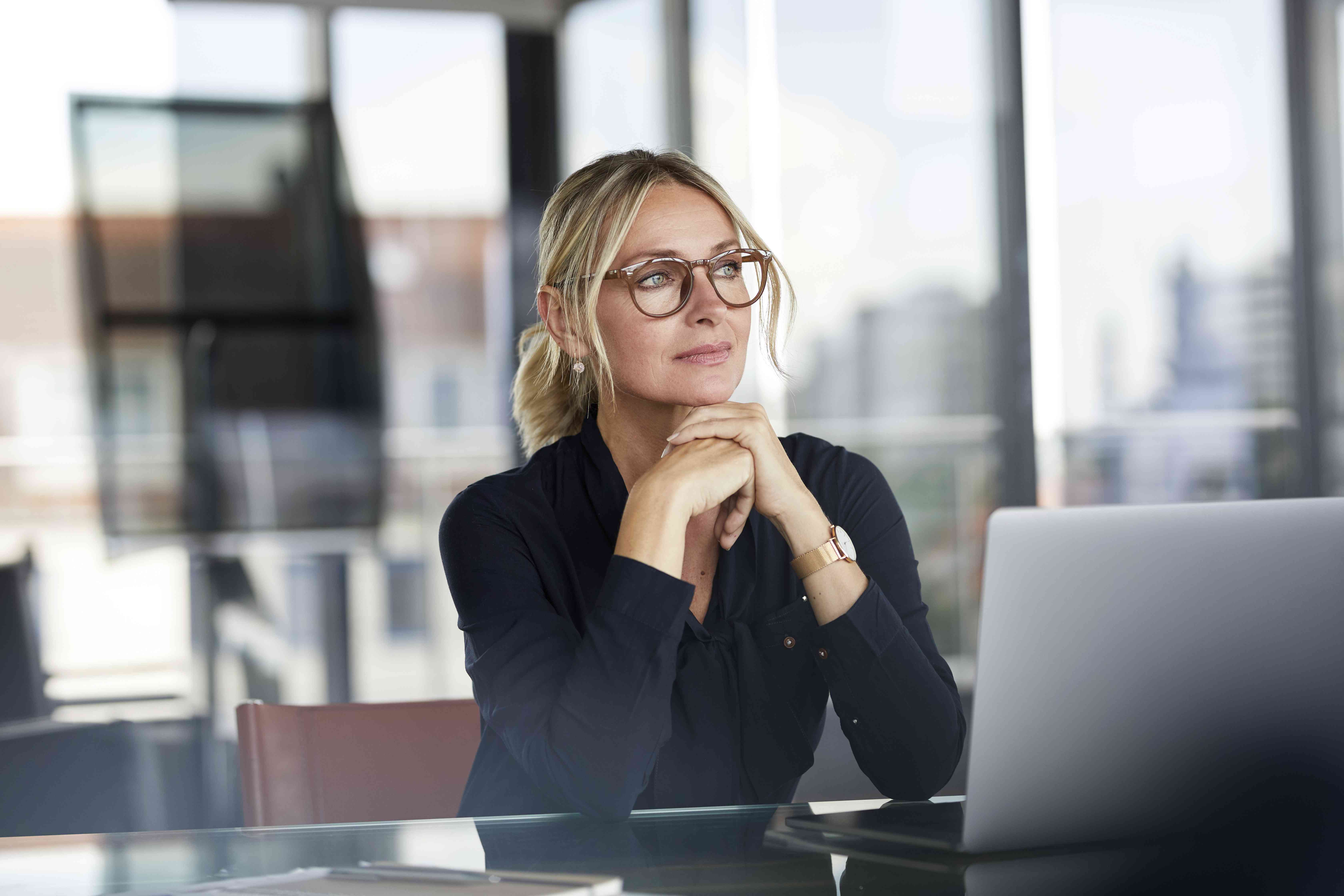 A woman in an office setting reflects.