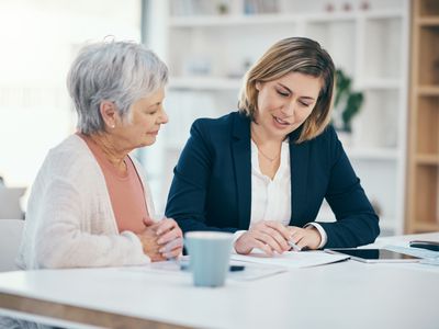 A financial advisor sits at a dining room table and talks with a mature adult client about rolling their TSP into a Roth IRA plan.