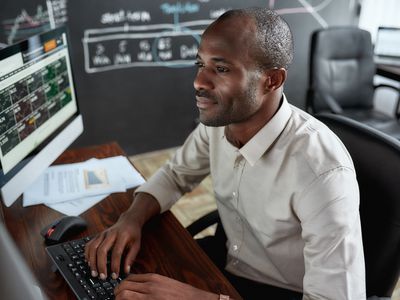 A stock trader reviews financial data on several computer monitors.