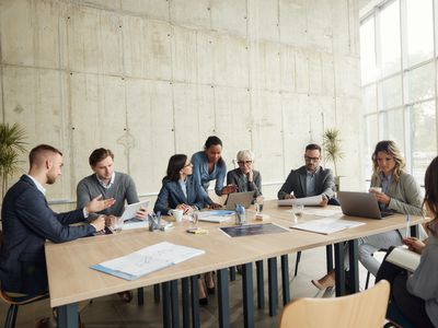 Corporate team at conference table discussing a takeover bid