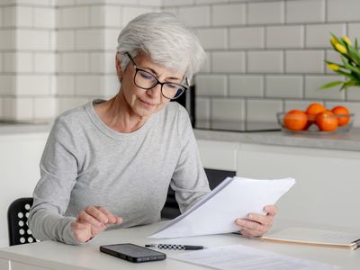 Older woman sitting at her kitchen table and looking at financial documents